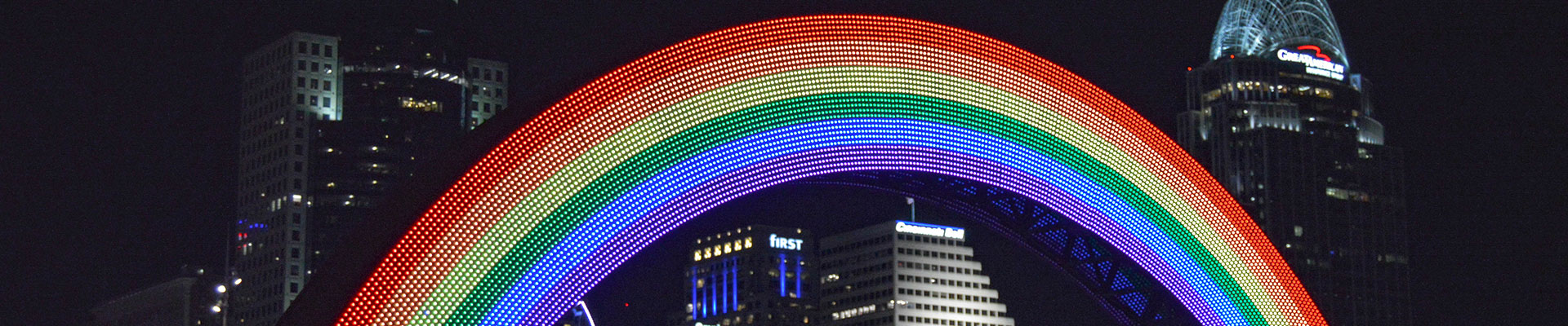 A picture of the Cincinnati skyline at night with rainbow LED lights.