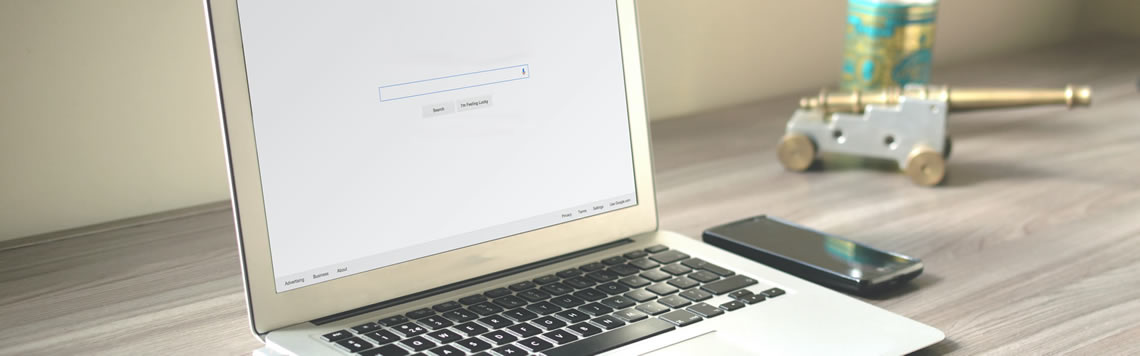 An image of a laptop open on a desk with a browser opened to a search engine.