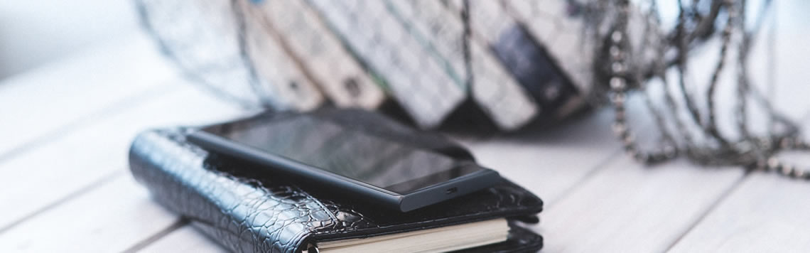 A photo of a cell phone on top of a day planner.